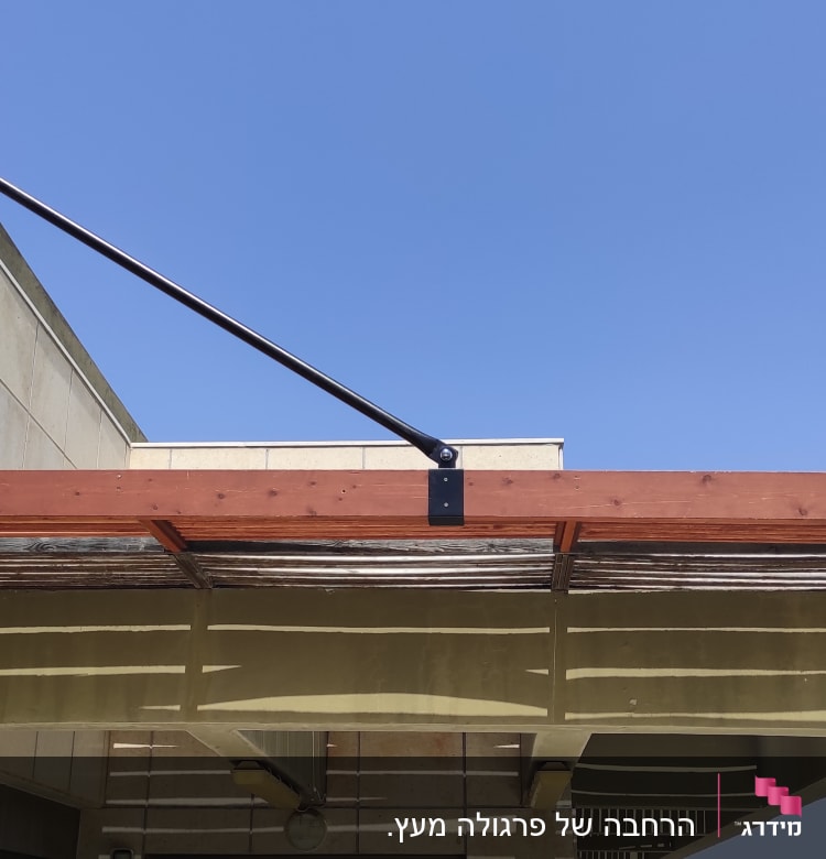 פרגולה מעץ עם חיפוי במבוק על קיר חיצוני